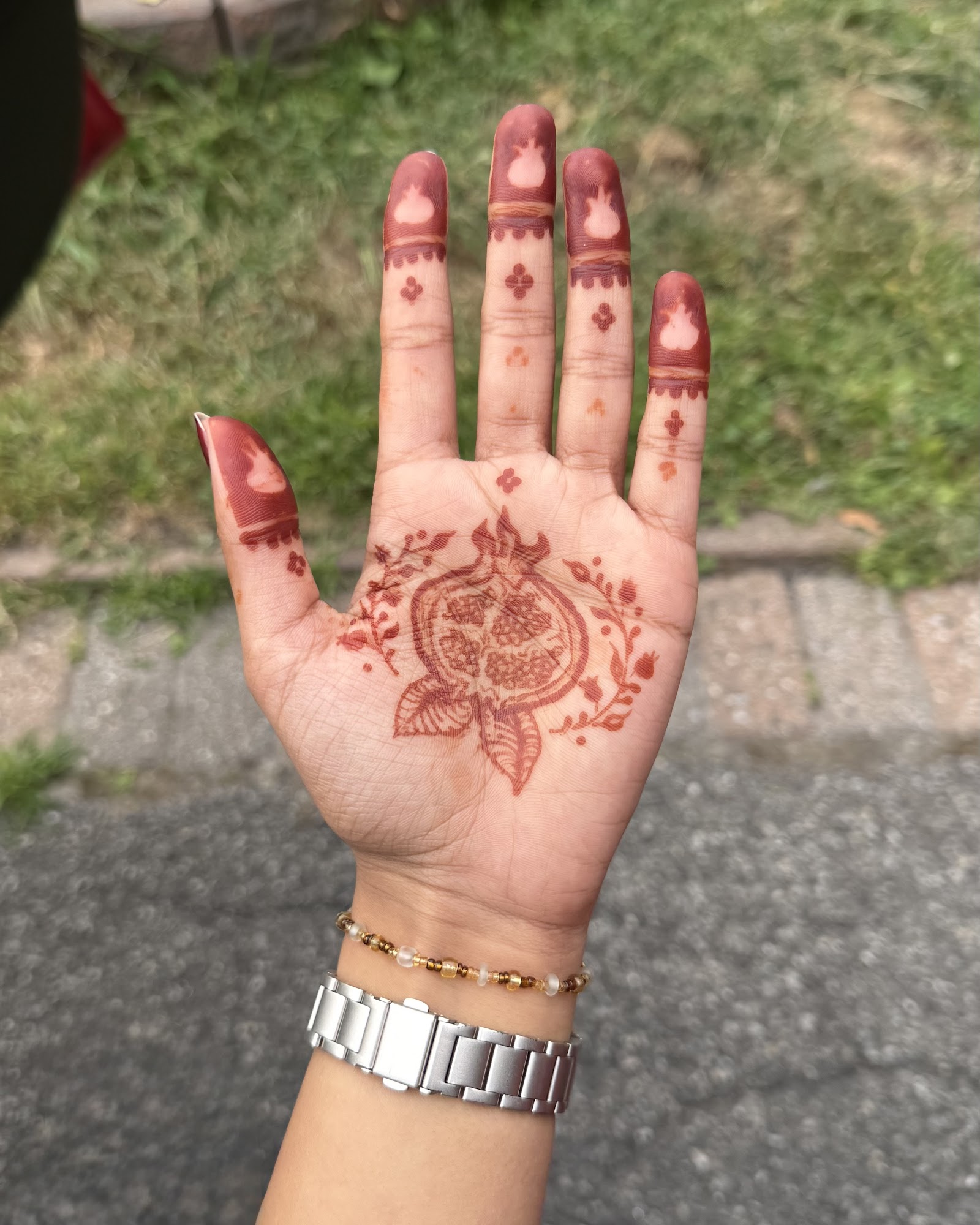 A close-up of an ornate NooniDesigns henna design on a hand.